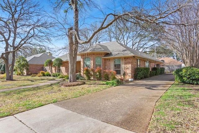 view of front of house with brick siding, driveway, and a front lawn