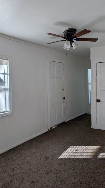 empty room with crown molding and dark carpet