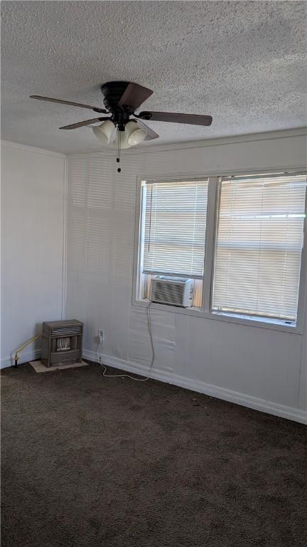 empty room with ceiling fan, cooling unit, dark carpet, and a textured ceiling