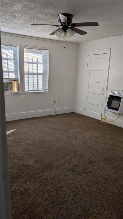 spare room with a textured ceiling, heating unit, dark carpet, and ceiling fan