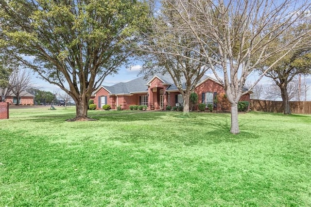 single story home with a front lawn, fence, and brick siding