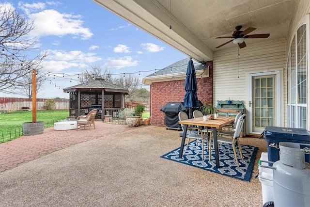 view of patio with outdoor dining area, a grill, a ceiling fan, fence, and a gazebo