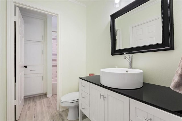 bathroom featuring toilet, a bathtub, wood finished floors, and vanity