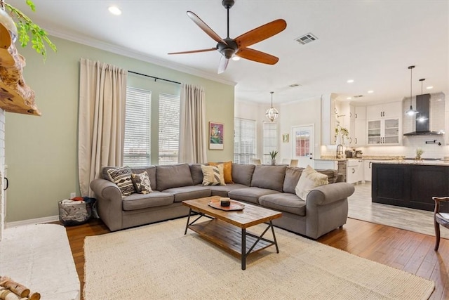 living room featuring ceiling fan, recessed lighting, visible vents, light wood finished floors, and crown molding