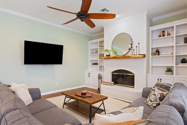 living room with a fireplace, wood finished floors, visible vents, and crown molding