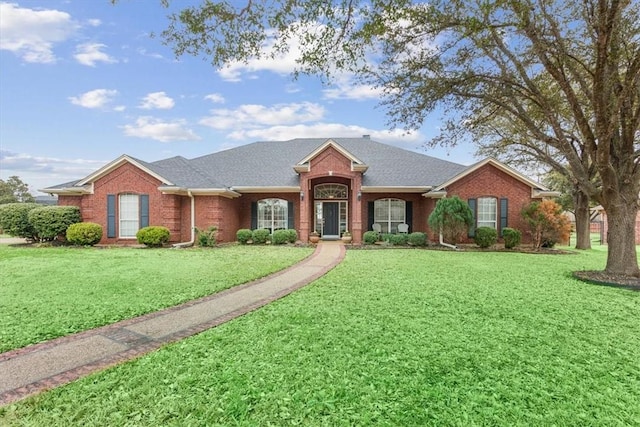 ranch-style house with a front yard, brick siding, and roof with shingles