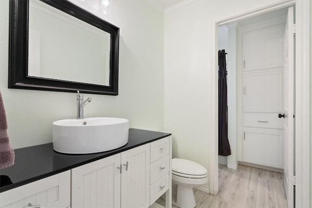 bathroom featuring ornamental molding, wood finished floors, vanity, and toilet