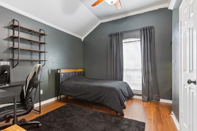 bedroom featuring wood finished floors, a ceiling fan, baseboards, vaulted ceiling, and ornamental molding