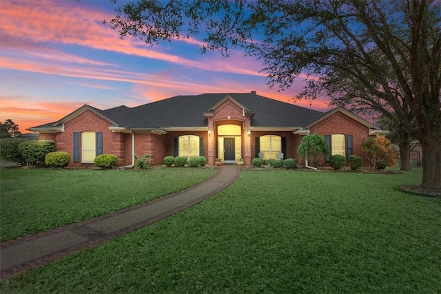 single story home with brick siding and a lawn