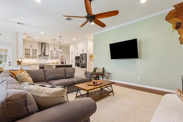 living area with recessed lighting, visible vents, baseboards, light wood-style floors, and ornamental molding