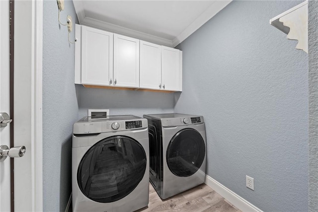 washroom featuring light hardwood / wood-style flooring, washer and dryer, crown molding, and cabinets