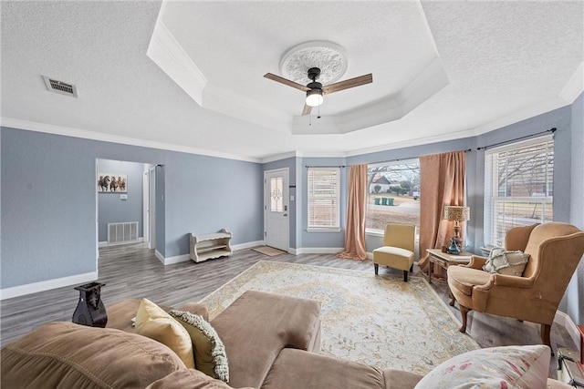 living room featuring a raised ceiling, ceiling fan, plenty of natural light, and hardwood / wood-style floors