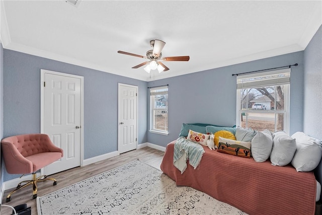 bedroom with ceiling fan, light hardwood / wood-style floors, multiple windows, and crown molding