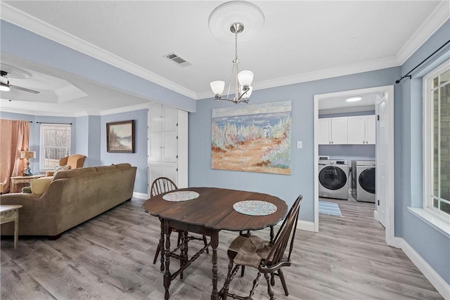 dining room featuring ceiling fan with notable chandelier, crown molding, washing machine and dryer, and light wood-type flooring