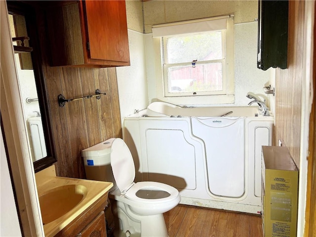 bathroom featuring a washtub, vanity, wood-type flooring, and toilet