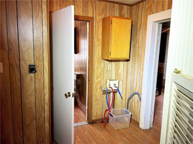 hall with light hardwood / wood-style floors and wood walls