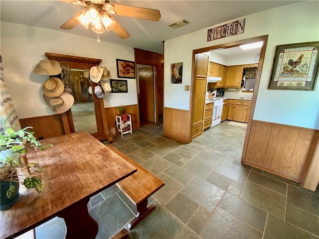 kitchen featuring white range, ceiling fan, and wood walls