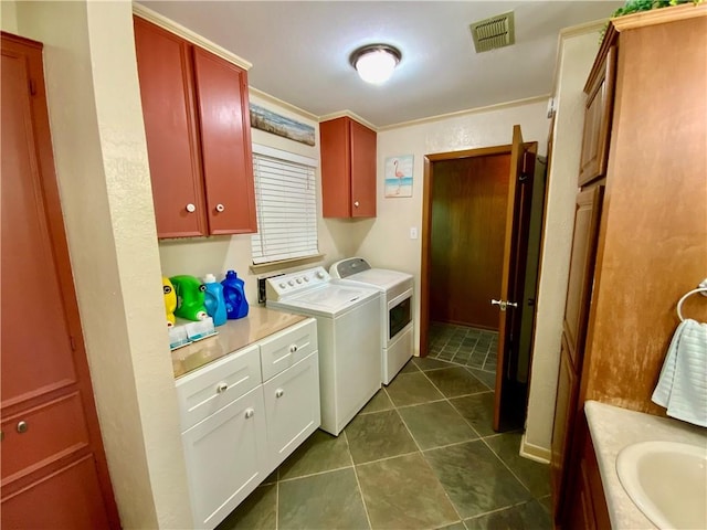 laundry room featuring cabinets, sink, crown molding, dark tile patterned floors, and washing machine and clothes dryer