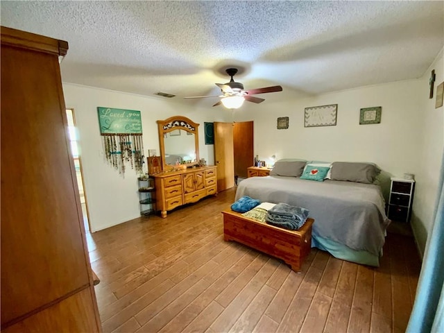 bedroom with hardwood / wood-style flooring, ceiling fan, and a textured ceiling