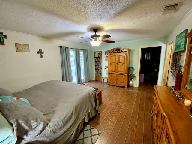 bedroom with ceiling fan, a textured ceiling, and hardwood / wood-style flooring