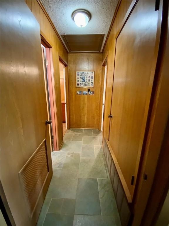 hallway with a textured ceiling and wood walls