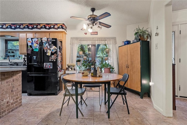 dining space with ceiling fan, sink, and a textured ceiling