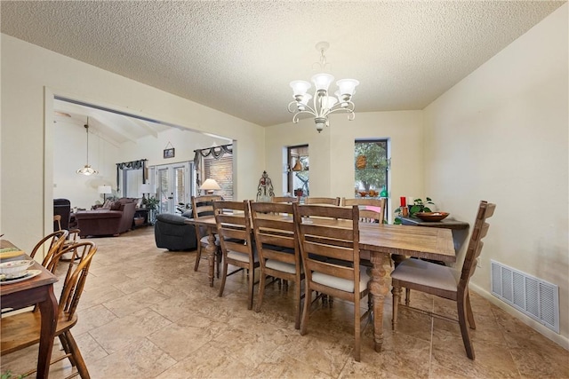 dining space with lofted ceiling, a textured ceiling, and an inviting chandelier