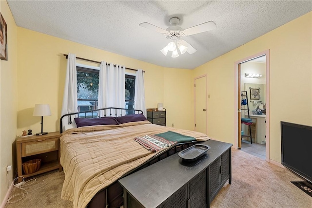 carpeted bedroom featuring a textured ceiling, ensuite bathroom, and ceiling fan