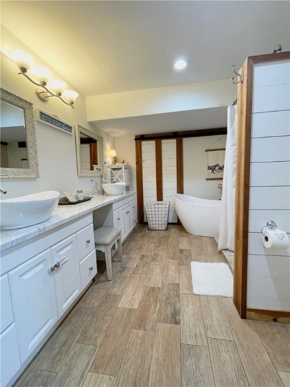 bathroom featuring hardwood / wood-style floors, vanity, and a tub to relax in