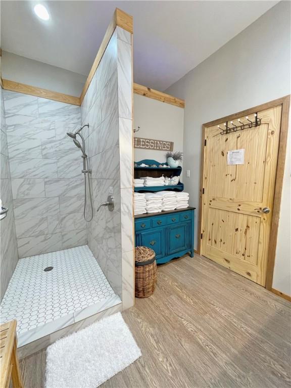 bathroom featuring hardwood / wood-style floors and a tile shower