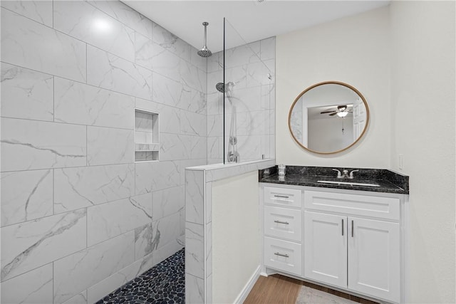 bathroom with hardwood / wood-style floors, vanity, ceiling fan, and a tile shower