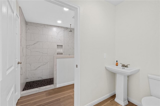 bathroom featuring tiled shower, hardwood / wood-style flooring, toilet, and sink