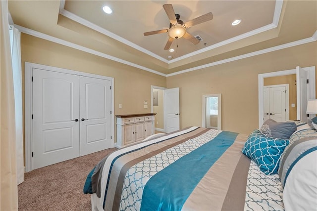 carpeted bedroom with a tray ceiling, ceiling fan, a closet, and crown molding