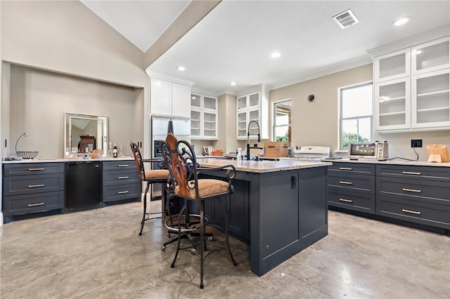 kitchen featuring a kitchen breakfast bar, white cabinetry, a kitchen island with sink, and sink