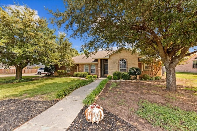 ranch-style house with brick siding, fence, and a front lawn