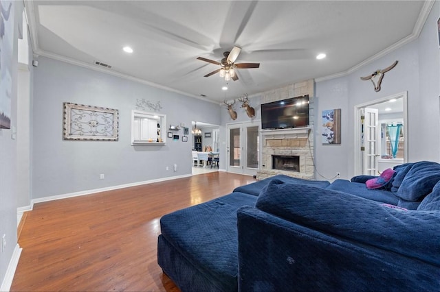 living room featuring a stone fireplace, hardwood / wood-style floors, and ornamental molding