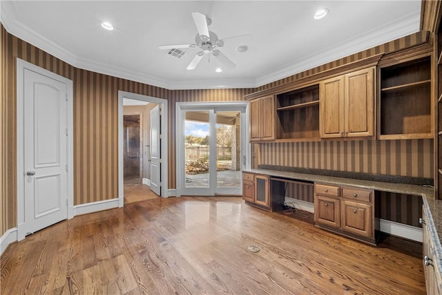 unfurnished office with built in desk, ceiling fan, ornamental molding, and hardwood / wood-style flooring