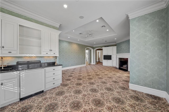 kitchen featuring a raised ceiling, crown molding, white cabinets, ceiling fan, and sink