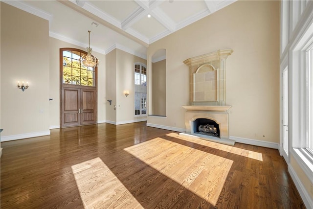 unfurnished living room with coffered ceiling, a healthy amount of sunlight, beamed ceiling, and dark hardwood / wood-style floors