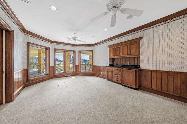 unfurnished living room with ceiling fan, crown molding, and light colored carpet