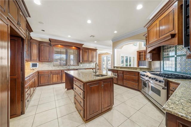 kitchen featuring ornamental molding, a center island with sink, range with two ovens, and sink