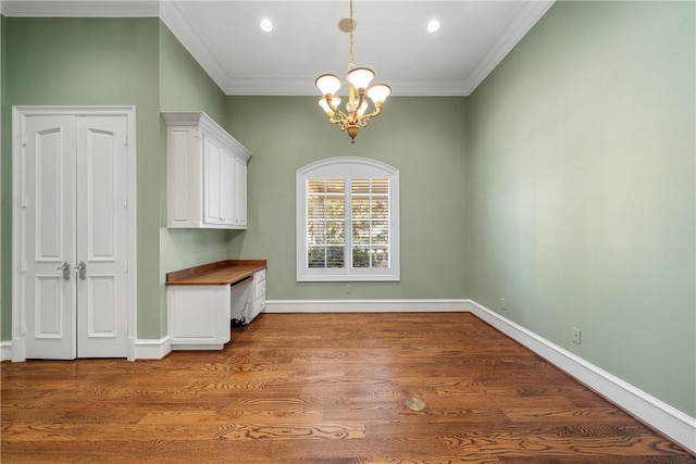 unfurnished dining area featuring an inviting chandelier, crown molding, and wood-type flooring