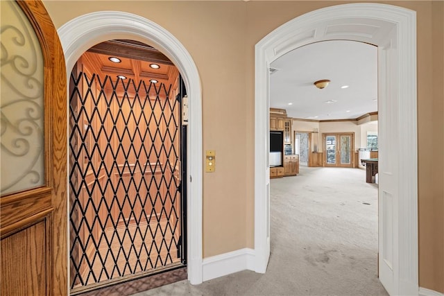 corridor with ornamental molding and light colored carpet