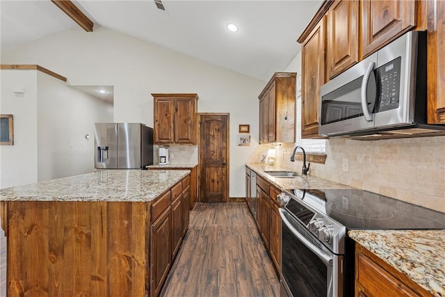 kitchen featuring vaulted ceiling with beams, a center island, light stone counters, appliances with stainless steel finishes, and a sink