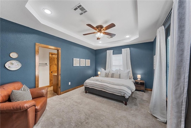 carpeted bedroom with visible vents, ceiling fan, baseboards, and a tray ceiling