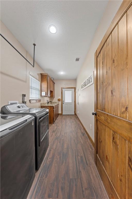 washroom featuring visible vents, dark wood-style floors, cabinet space, independent washer and dryer, and a sink