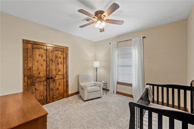 carpeted bedroom featuring a nursery area, visible vents, baseboards, and ceiling fan