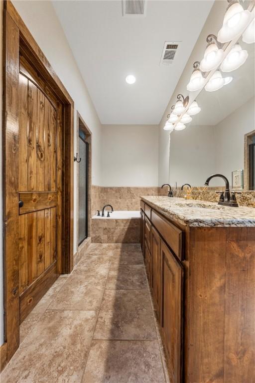 bathroom featuring a sink, a garden tub, visible vents, and a stall shower