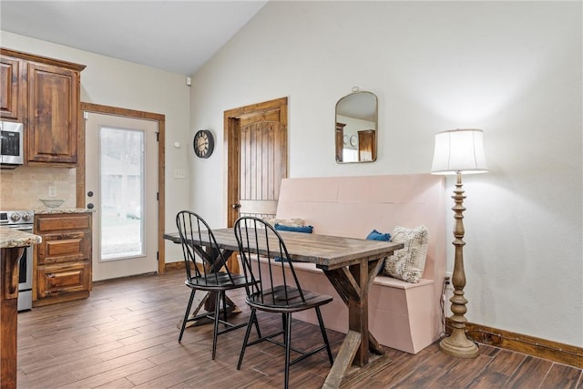 dining space with baseboards, dark wood-style floors, and vaulted ceiling