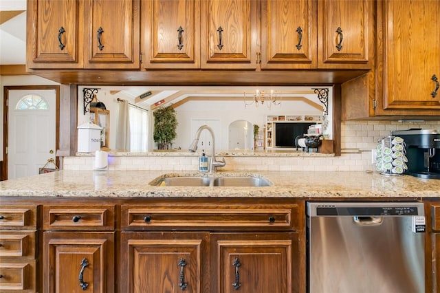 kitchen with sink, tasteful backsplash, light stone counters, stainless steel dishwasher, and a notable chandelier